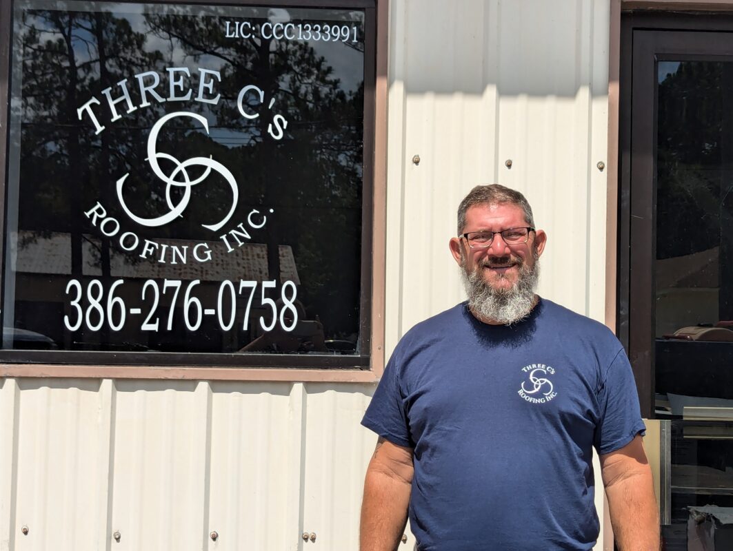 Scott Crider standing by Three C's Roofing sign